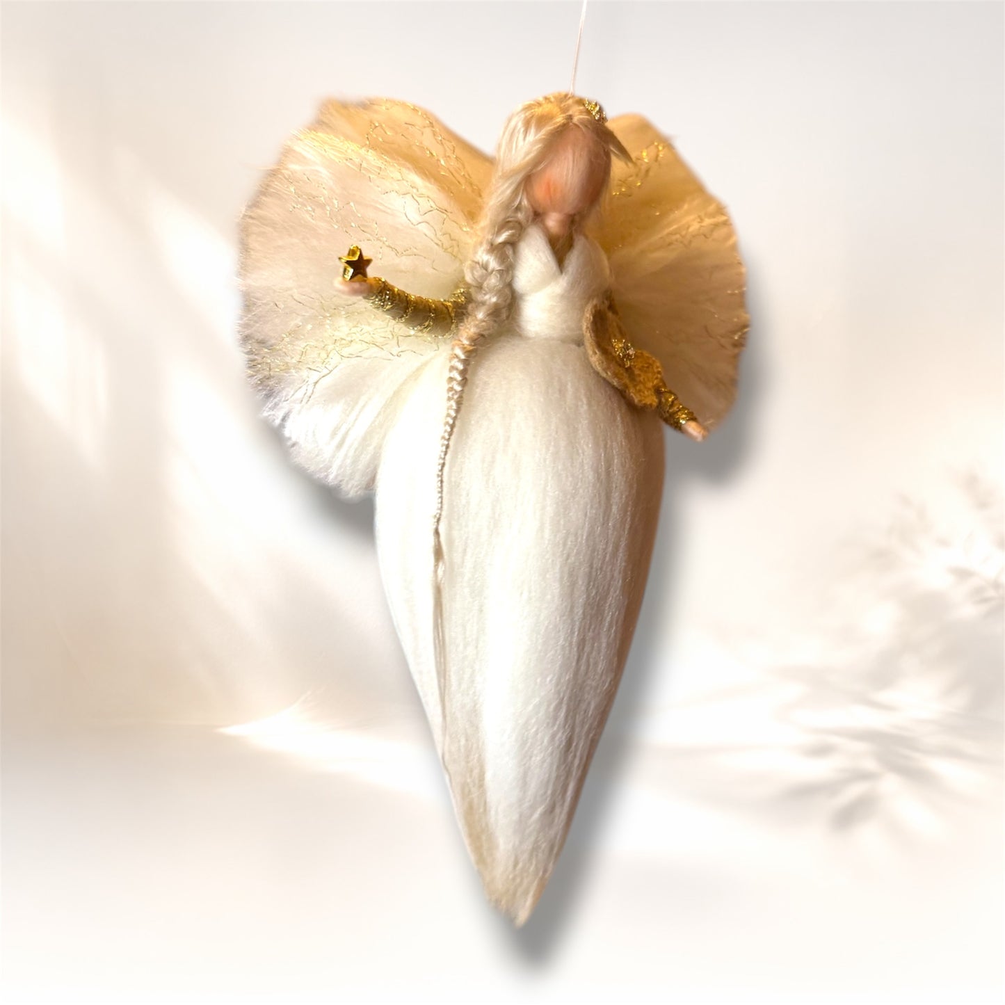 Håndlavet uldengel i hvid med gyldne detaljer set i vinkel med blomst og stjerne