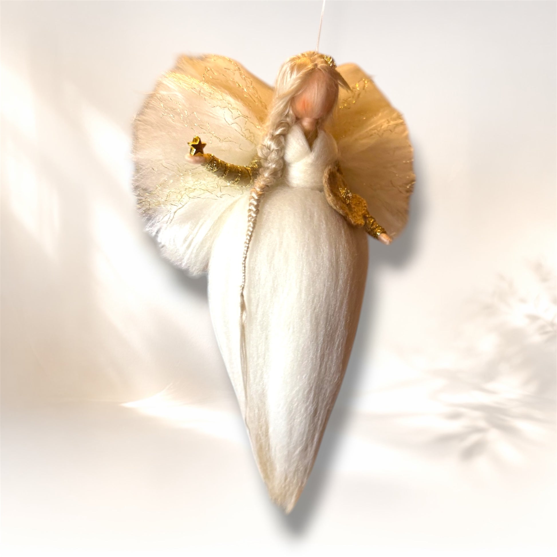 Håndlavet uldengel i hvid med gyldne detaljer set i vinkel med blomst og stjerne