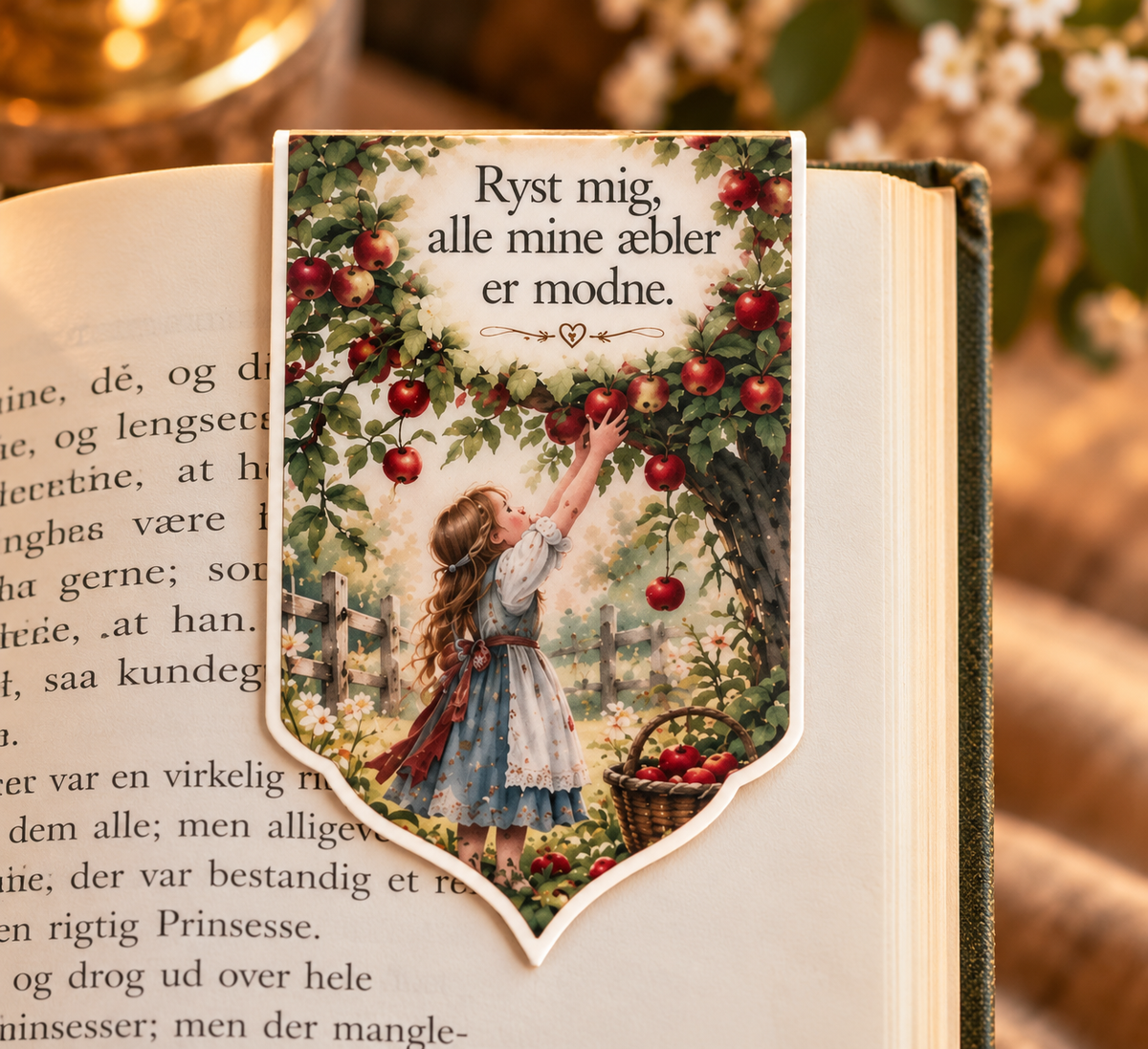 Magnetisk bogmærke inspireret af Mor Hulda med æbletræ og teksten “Ryst mig, alle mine æbler er modne” vist på en åben bog